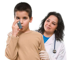 Young boy using an inhaler, with the doctor in the background
