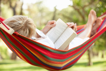 Woman relaxing in a hammock reading a book