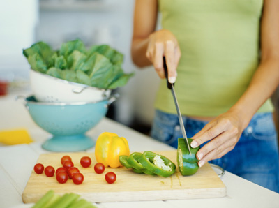 Mid-section view of a woman cutting vegetables. Image by © Royalty-Free/Corbis