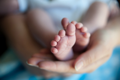 Close up of a mother holding her newborn's feet in one hand