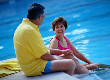 Older couple lounging at the side of a swimming pool