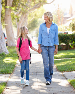 Mother and daughter walking to school on a suburban street
