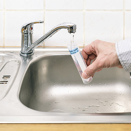 person drawing water from faucet for well testingTesting 