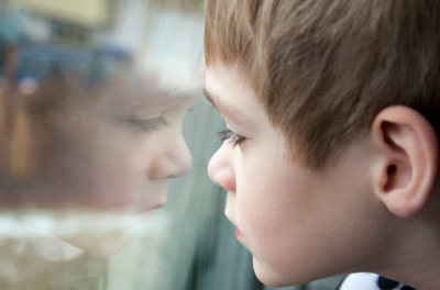 Little boy looking out a window, looking bored