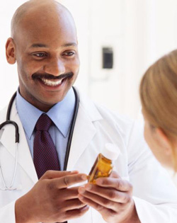 Physician holding a prescription bottle, talking to a patient.