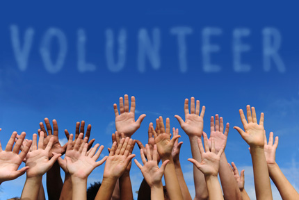 Multi-ethnic raised hands and writing volunteer