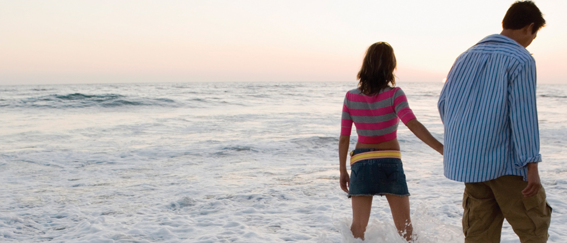 image of two people walking in the water at the beach.