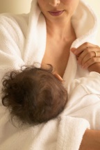 picture of a woman breastfeeding a baby while wearing a robe