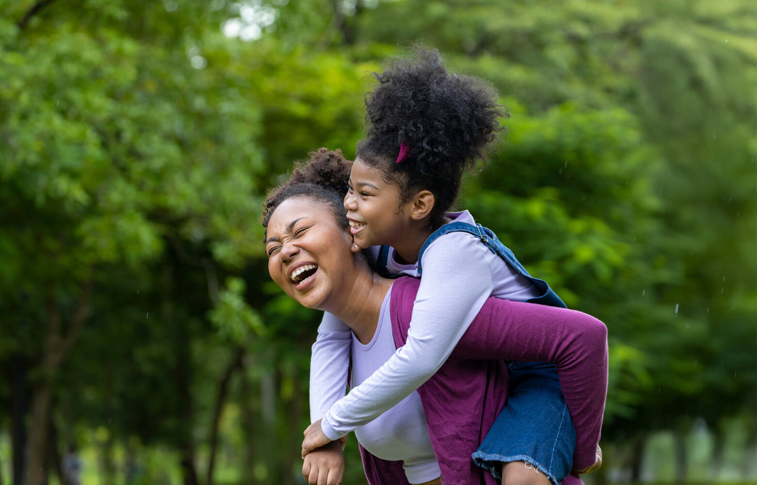 Smiling mother giving her daughter a piggyback ride