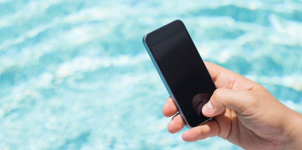 Holding a Phone While Standing Next to a Swimming Pool