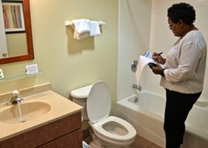 woman completing inspection forms in while reviewing bathroom