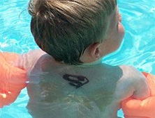 child in pool with black henna tattoo on back