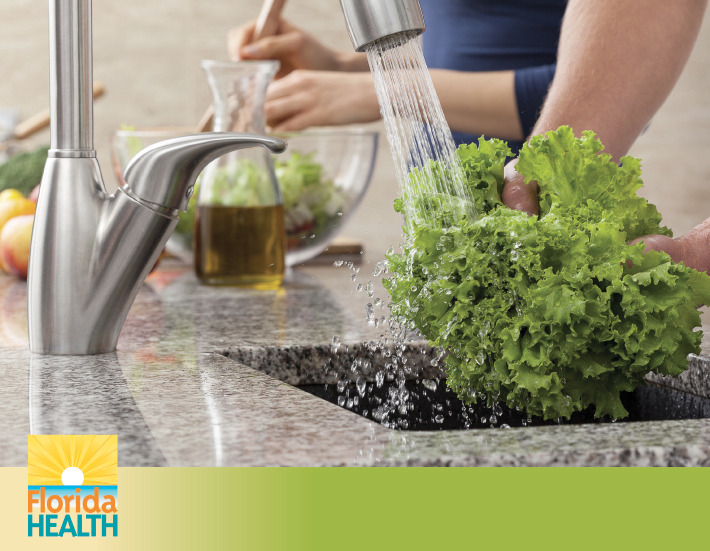 person washing lettuce in kitchen sink
