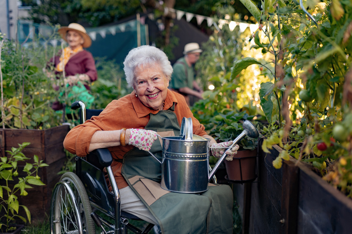 Senior holding watering can in a community garden
