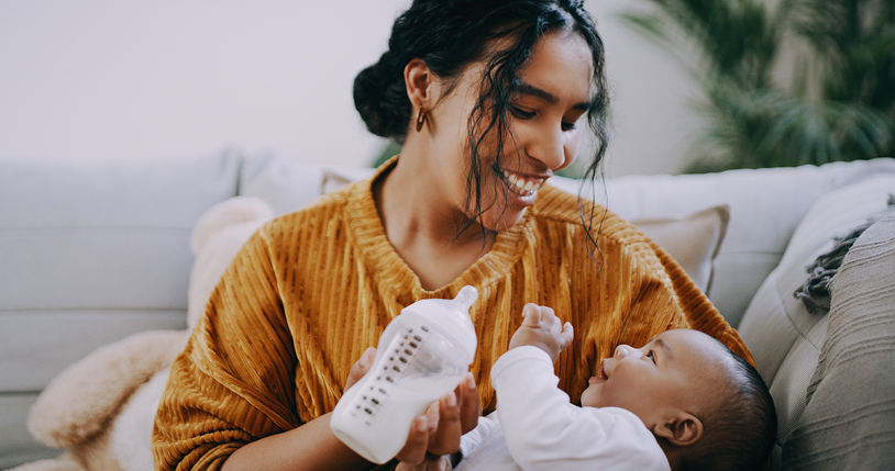 Mother feeding child milk in a baby bottle