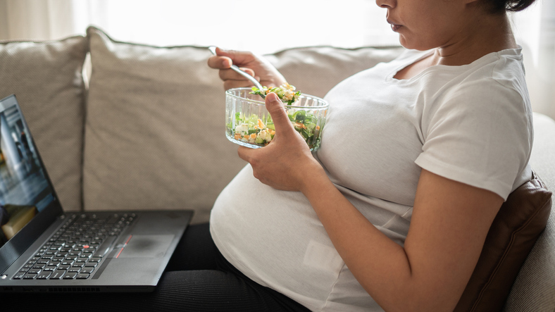 Pregnant woman eating a salad during telehealth appointment