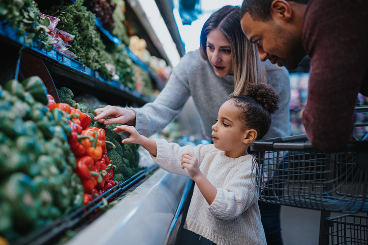 Family in vegetable aisle of grocery store