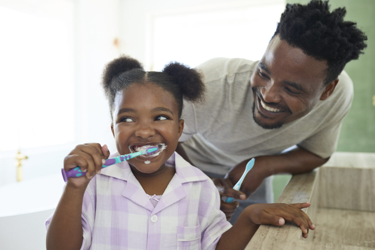 Father and daughter brushing teeth together