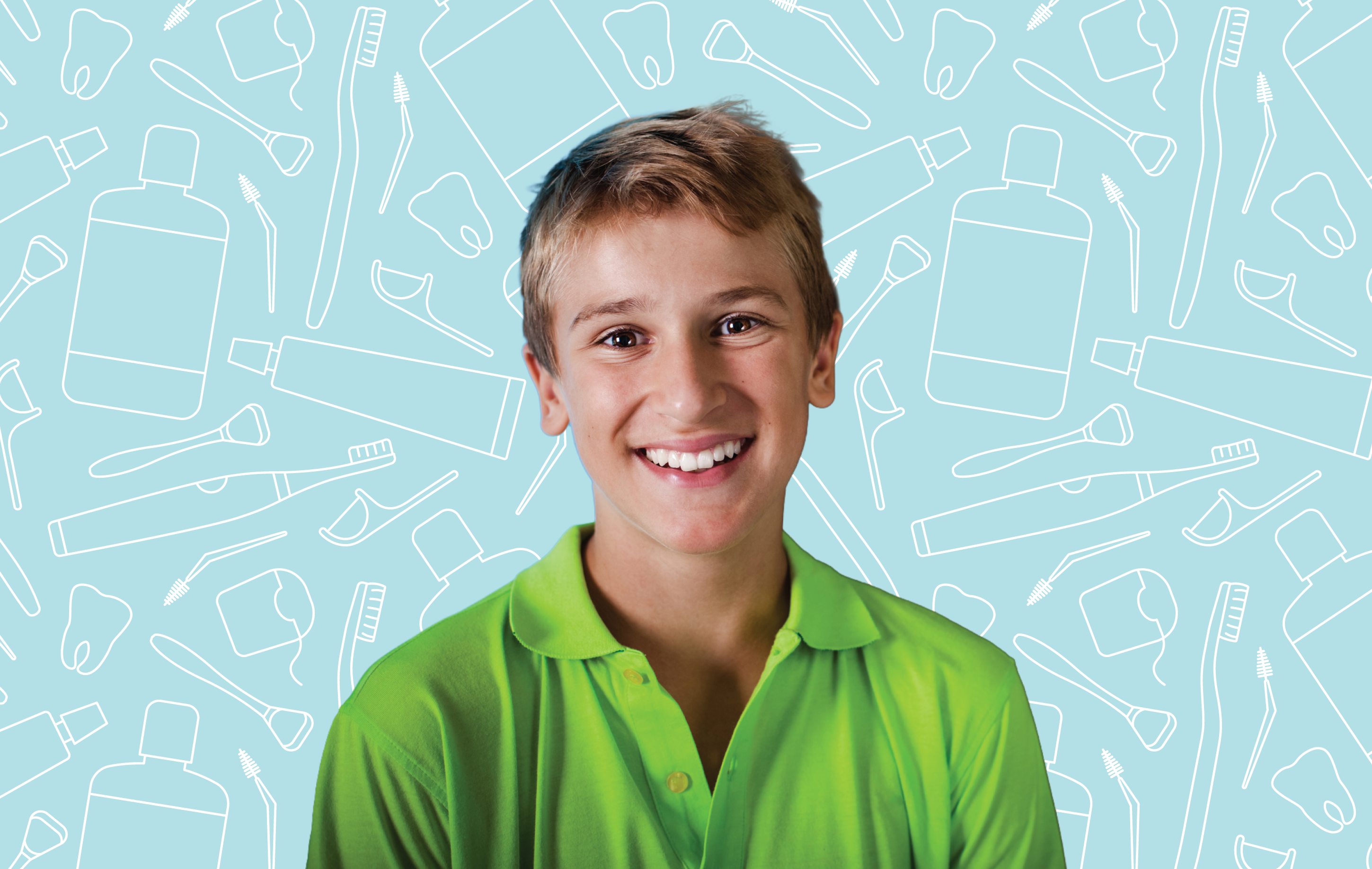 A young boy smiling sitting in front of dental hygiene products