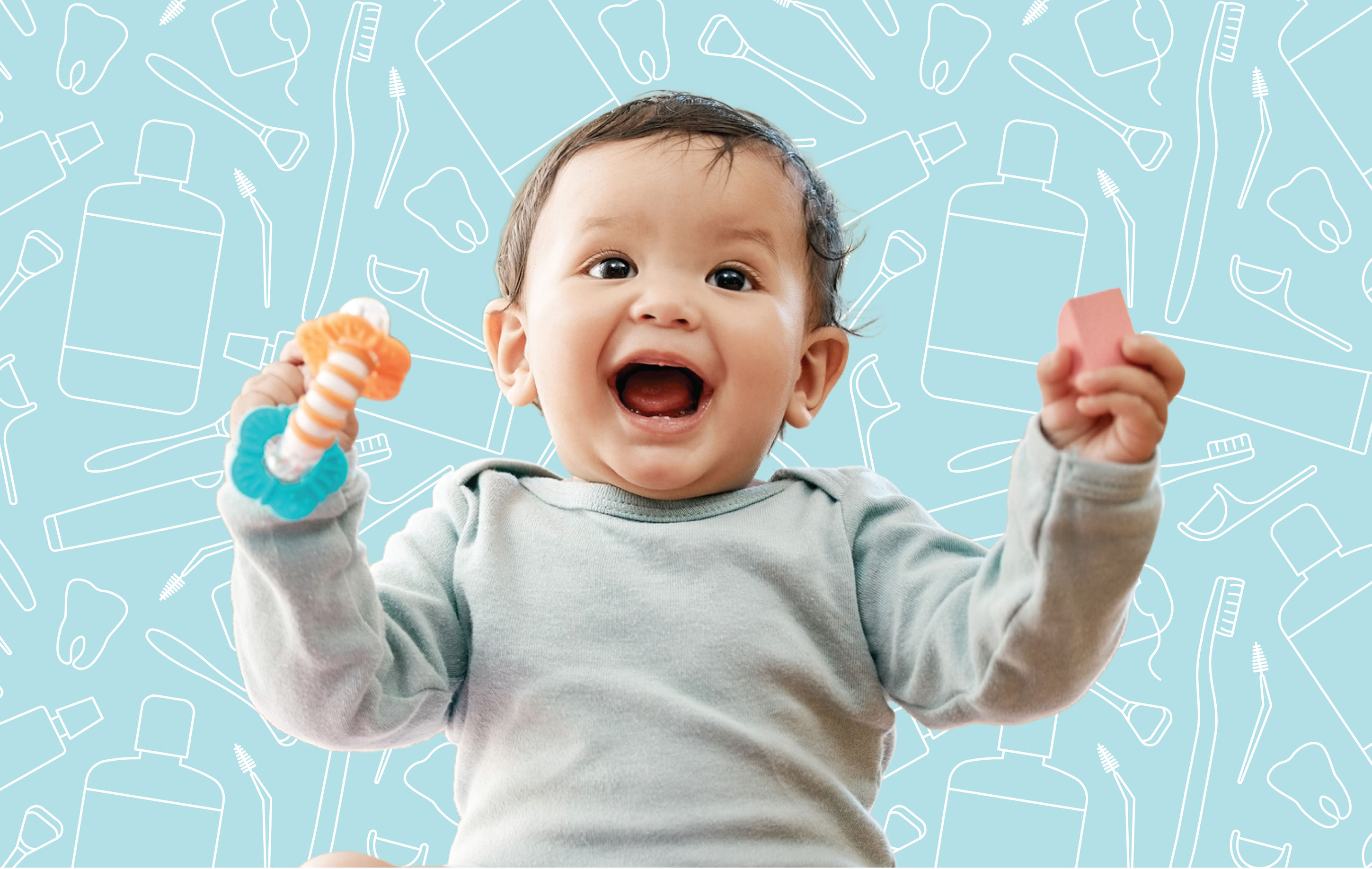 A laughing infant holding a teether and a pink block sitting in front of dental hygiene products