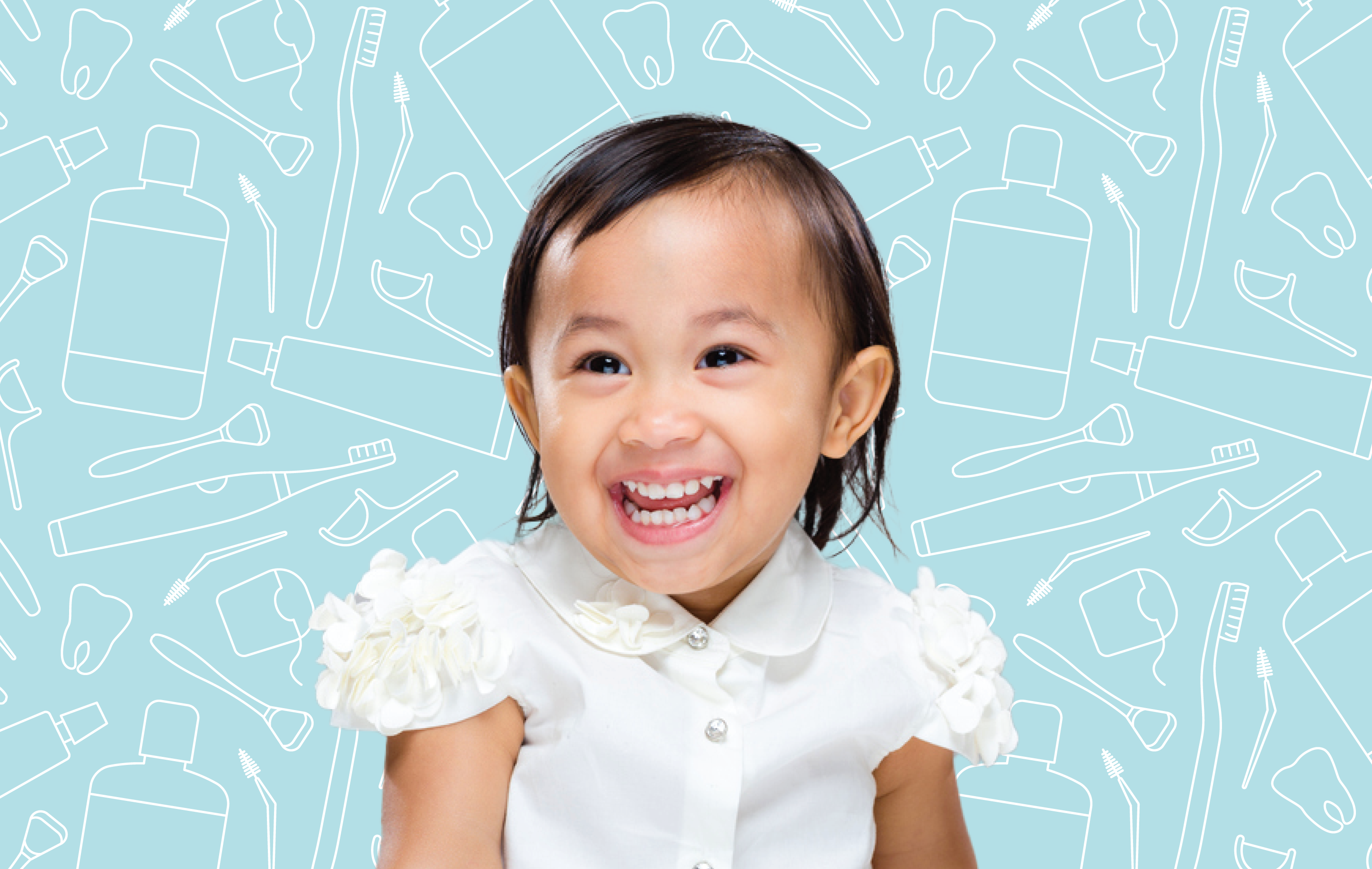 A smiling child with dark hair and a white shirt sitting in front of dental hygiene products