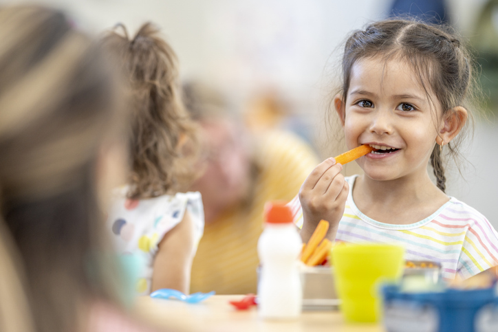 A young girl eating a carrot stick 