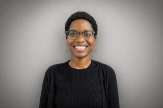 Headshot of a smiling woman with short dark hair and glasses.
