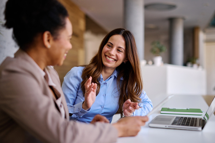 Two women smiling and talking at work