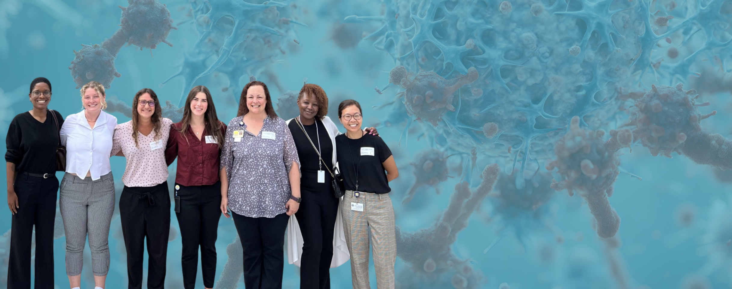 Seven smiling women of diverse backgrounds standing together against a blue background 