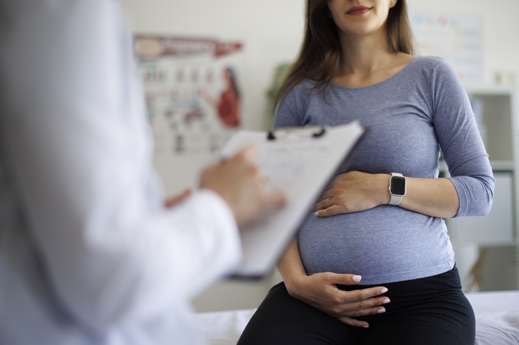 A pregnant woman facing a doctor who is taking notes