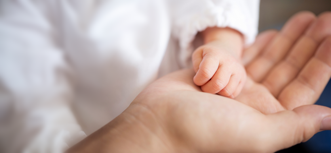 Close-up of a baby's tiny hand resting in the hand of the mother